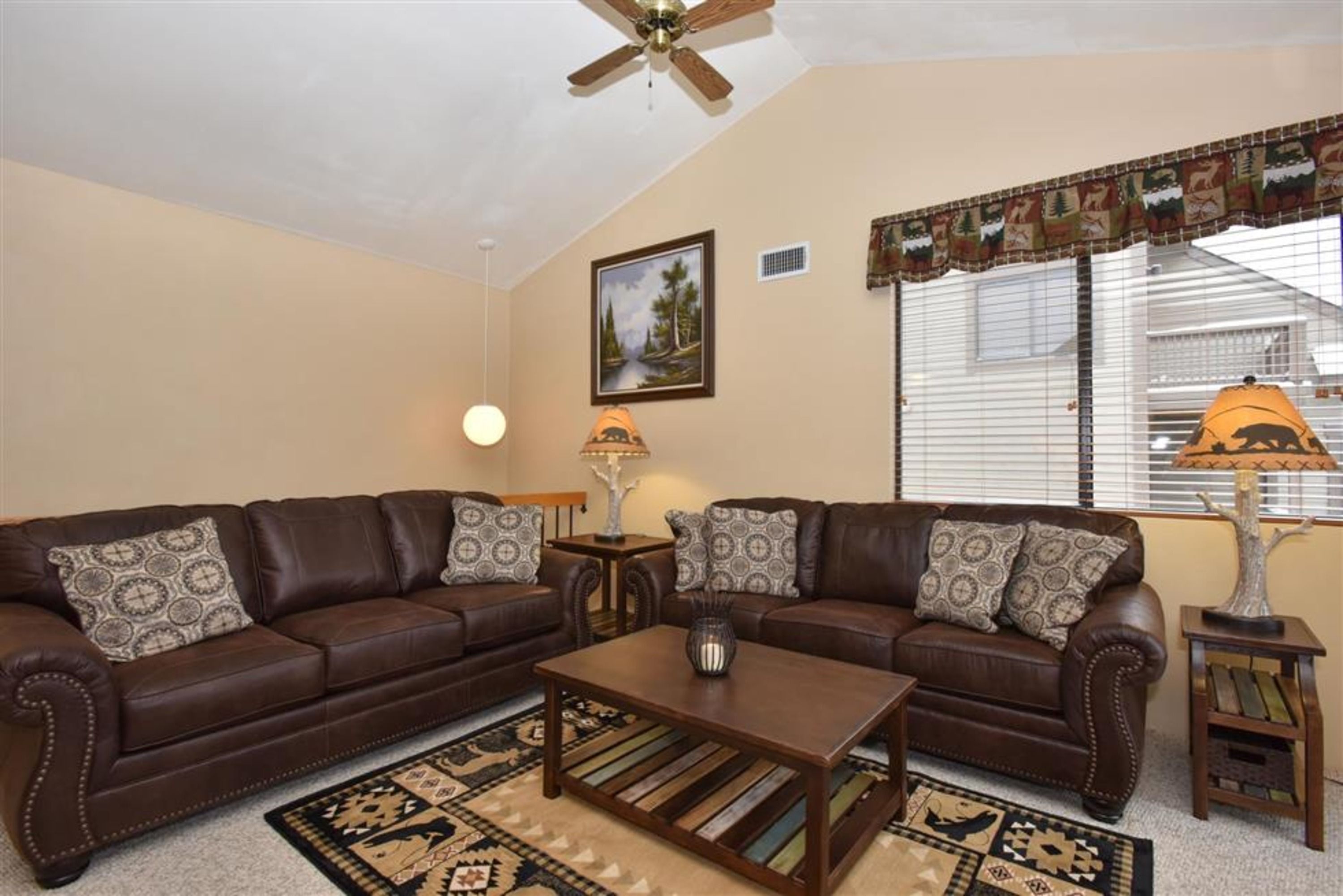image Bright and inviting living area with mountain lodge décor and sleeper sofa for extra guests.