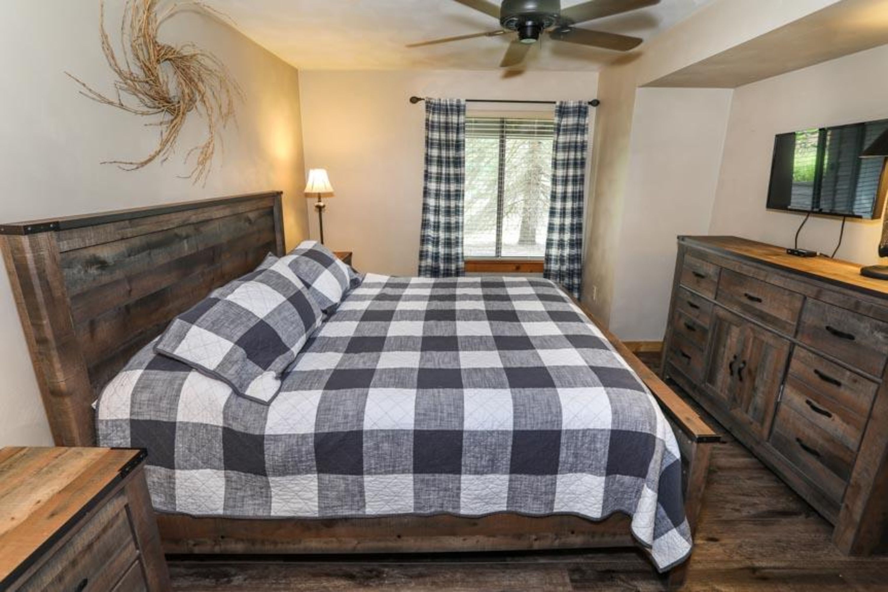 image Stylish main bedroom with queen bed, wood accents, and streaming-ready smart TV.