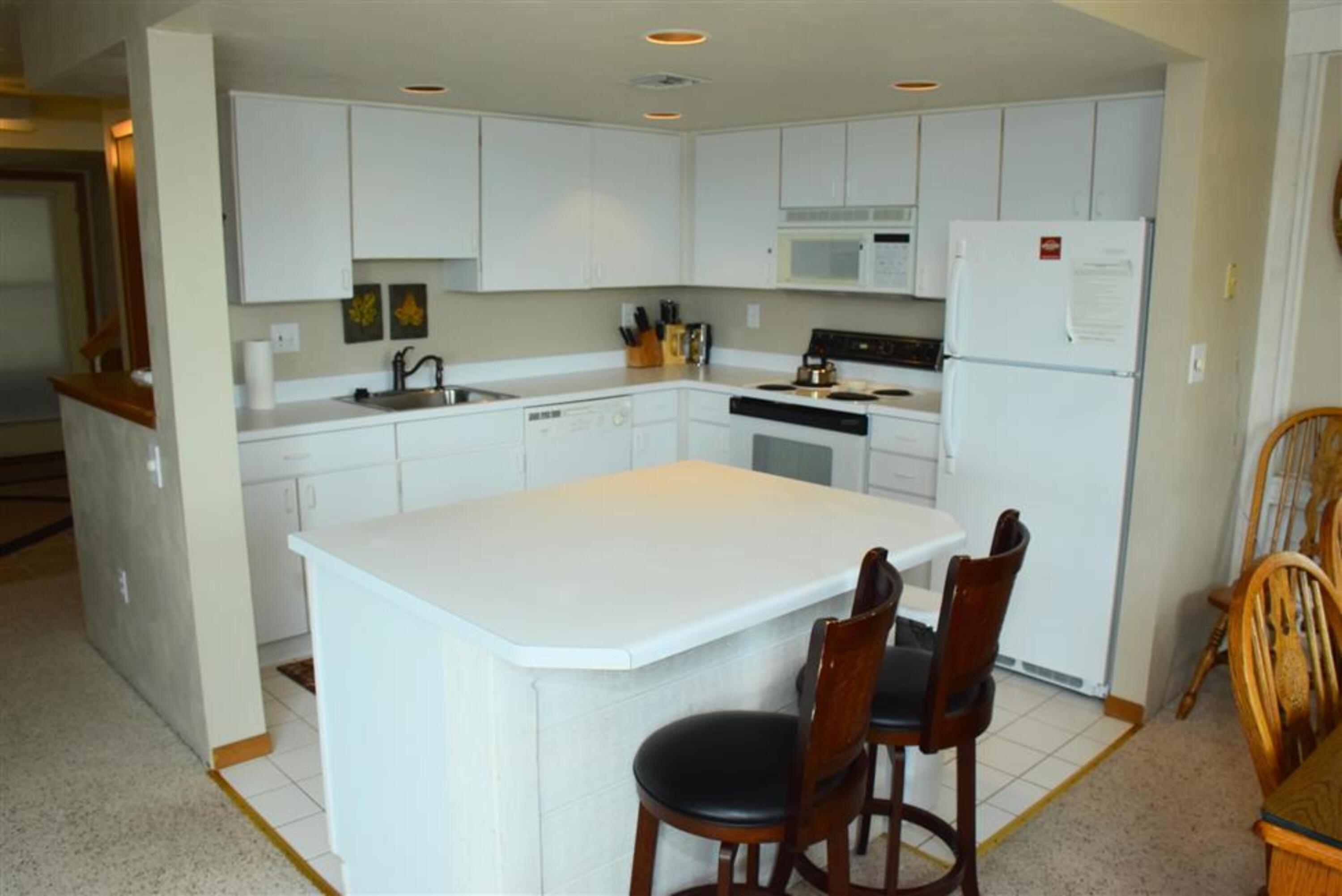 image Fully equipped kitchen featuring modern appliances and a central island with bar seating for casual dining.