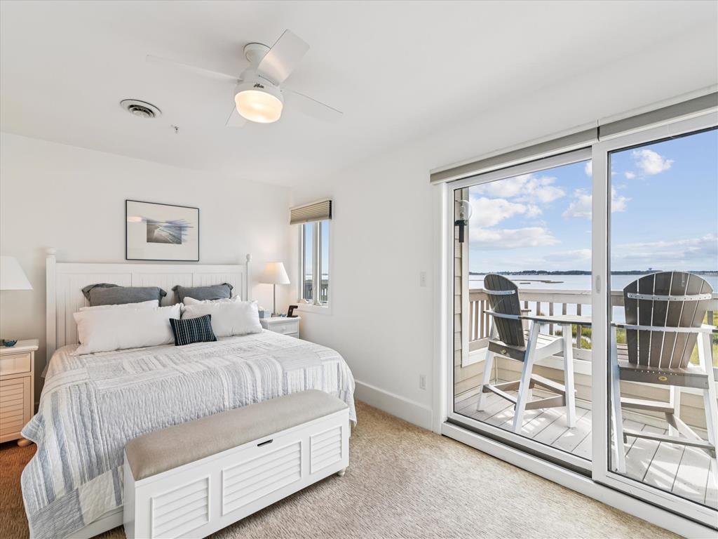 image The airy master bedroom invites you in with abundant natural light and coastal-inspired decor, complete with a private balcony overlooking serene water views.