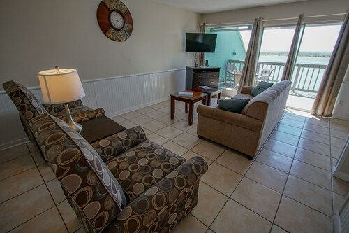 image Bright and breezy living room with large windows that frame the peaceful waters of the bay—your perfect spot to unwind and soak in coastal calm.