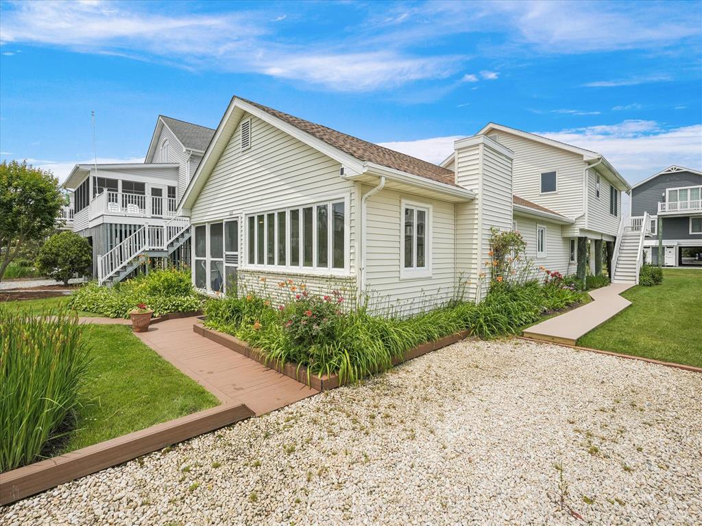 image The front exterior of this Bethany Beach four-bedroom home showcases a welcoming screened porch and classic coastal architecture.