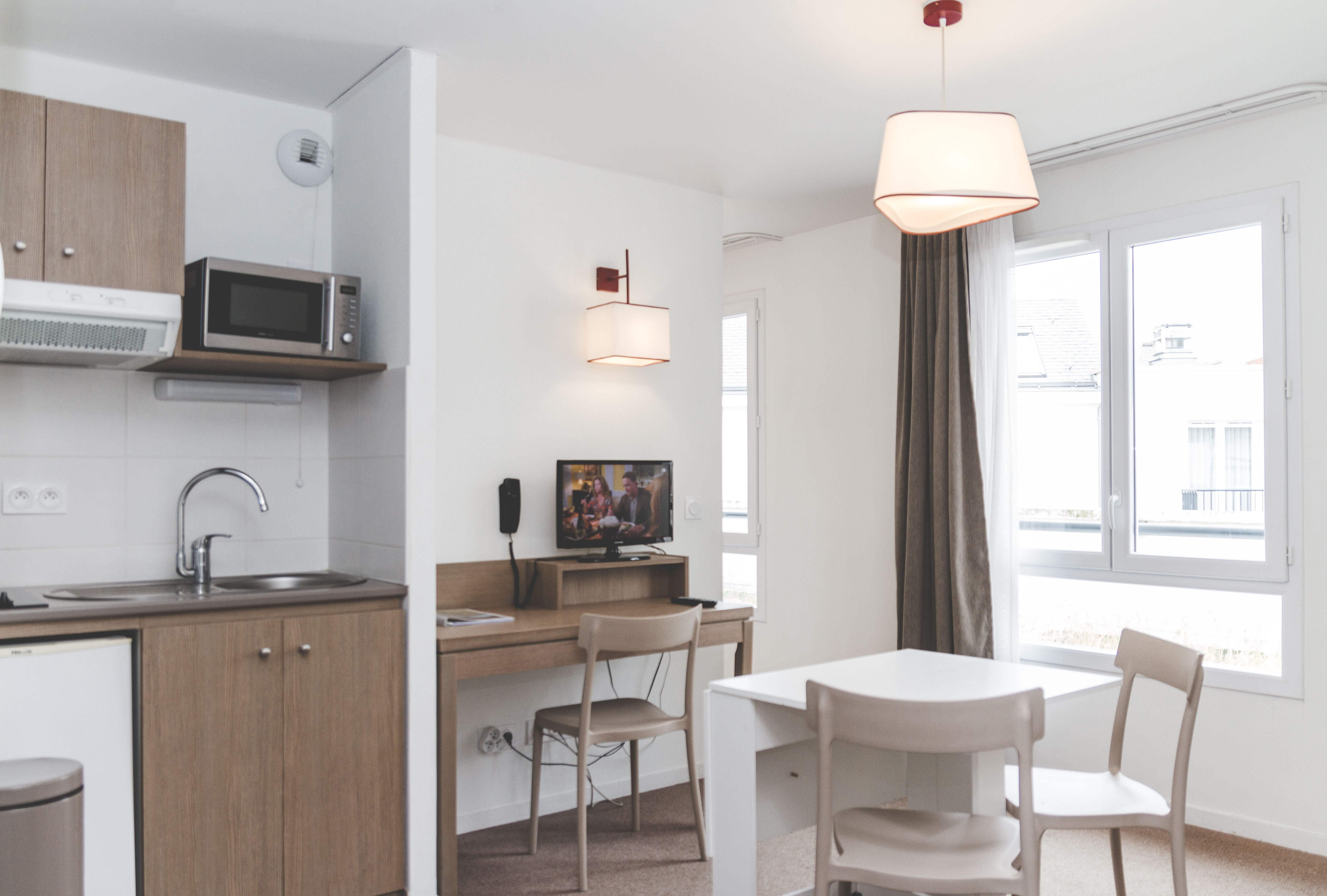 image A bright open-plan living space combines a fully equipped kitchenette with a cozy dining area, perfect for relaxed city stays.