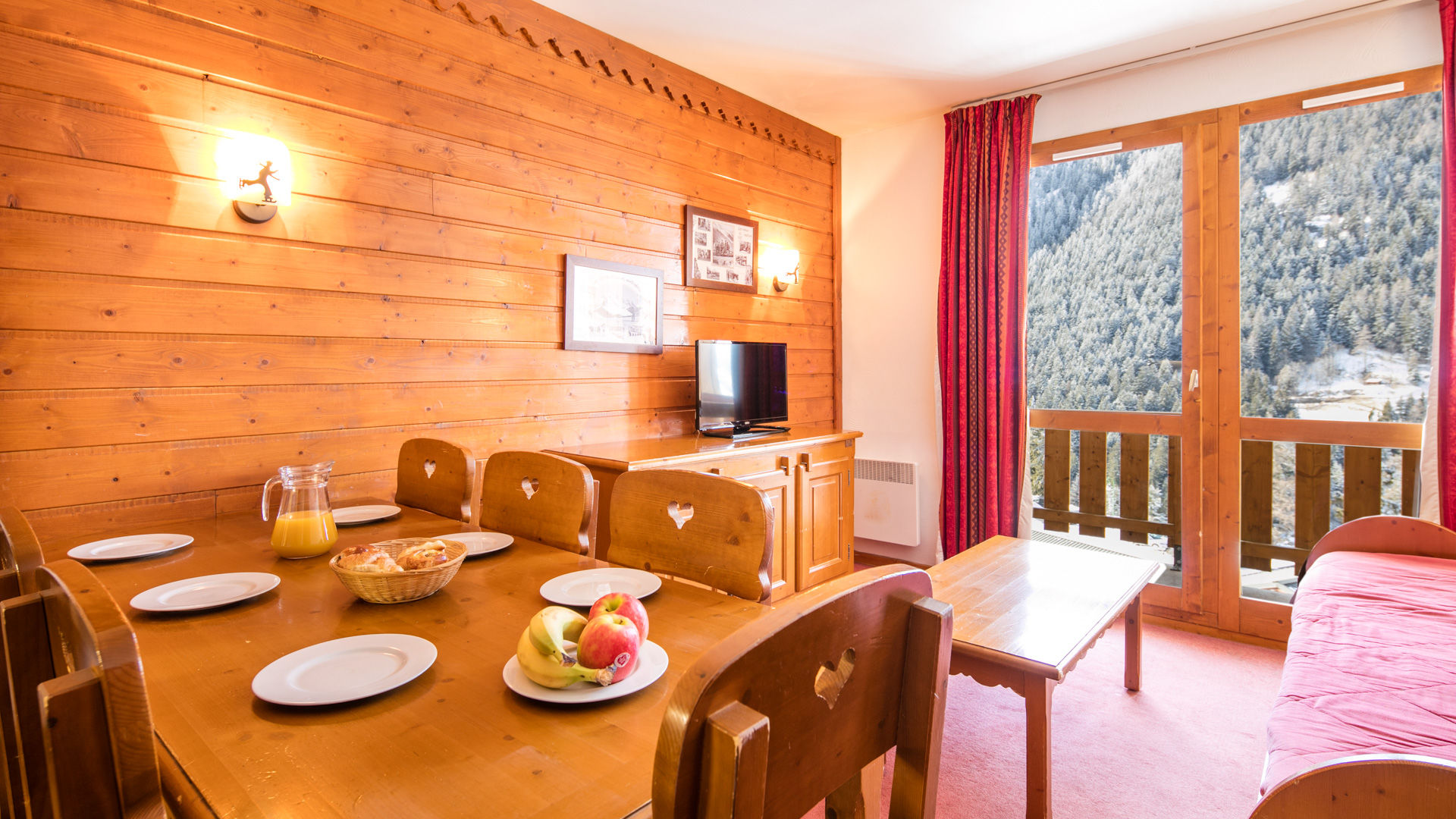 image Bright alpine-style living room with dining table and balcony overlooking the mountains — perfect for cozy family meals.