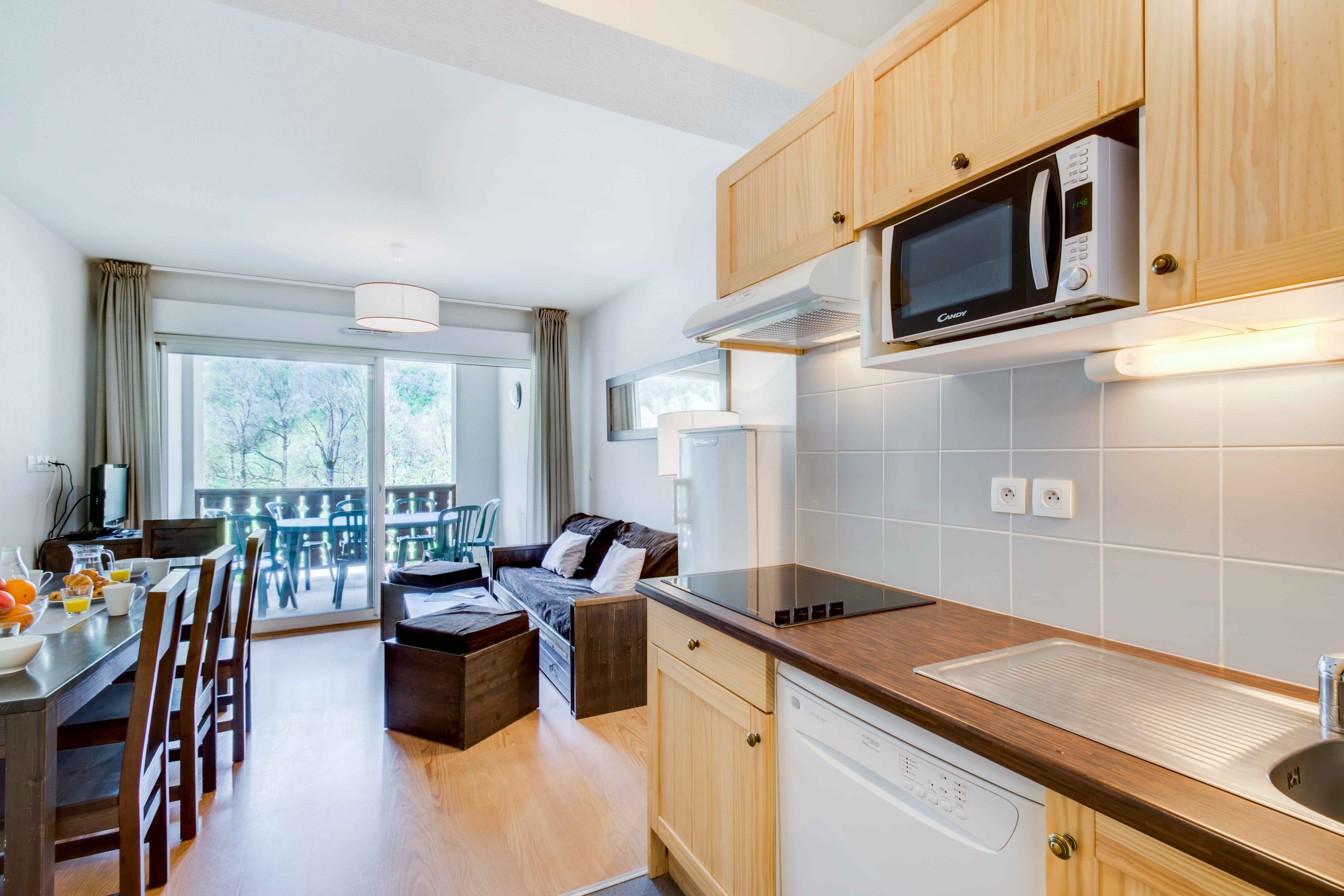 image Bright and fully equipped kitchen with everything you need to prepare family meals — including a microwave, dishwasher, and dining area opening onto the living space. Perfect for cozy dinners after a day exploring the mountains.