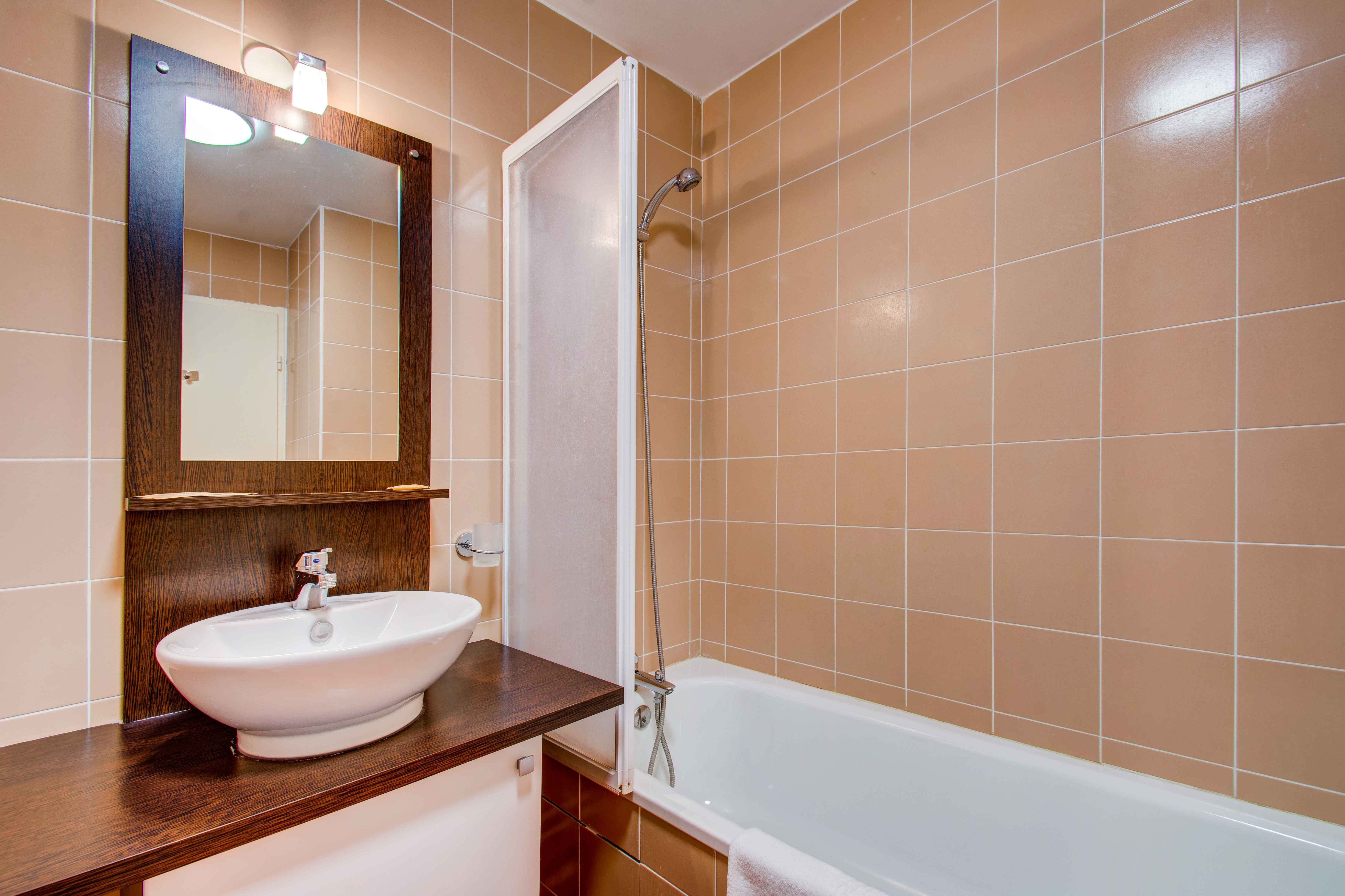image Private bathroom featuring a bathtub, sink, and mirror — perfect for relaxing after a day on the pistes.