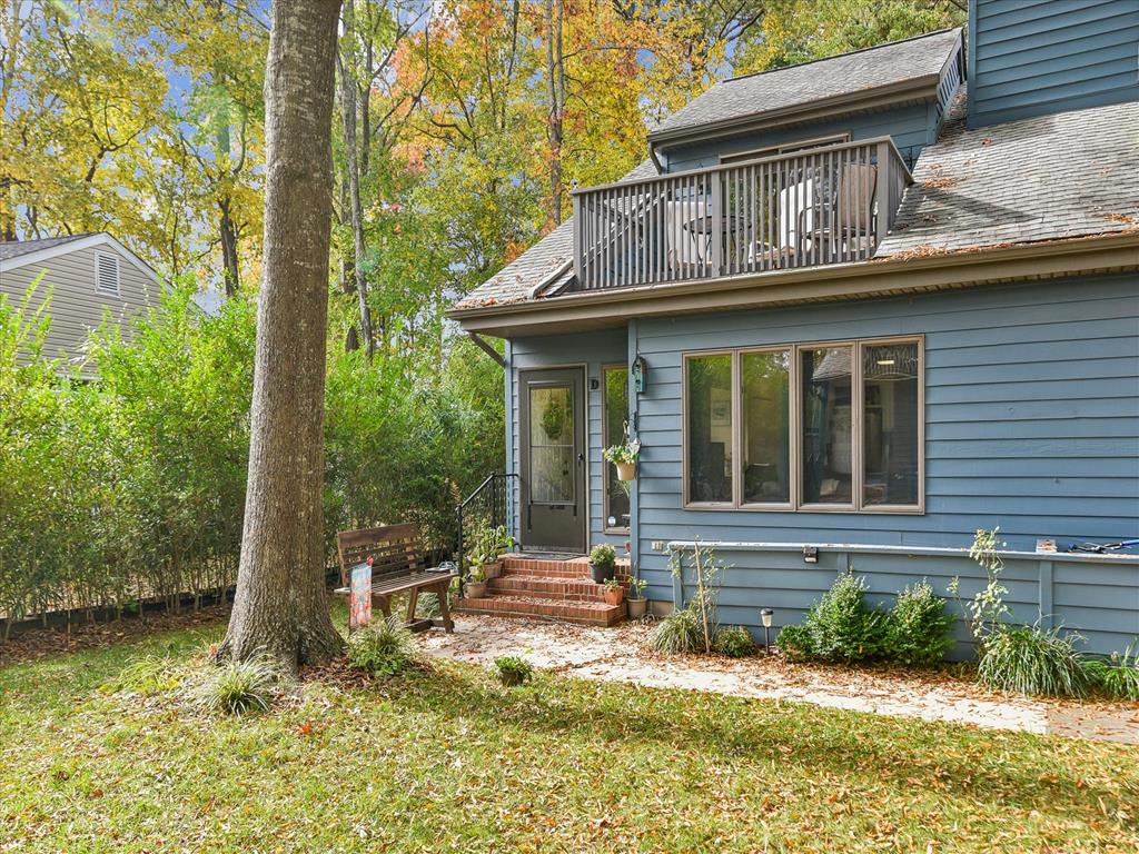 image Front entrance displays a staircase leading to the door, with potted plants and a bench on the lawn