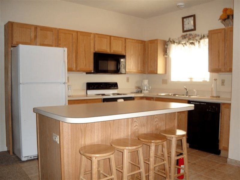 image Cozy full kitchen with warm wood cabinetry, bar seating, and all the essentials for easy home-style dining.