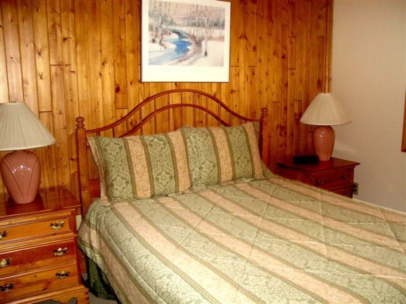 image Inviting bedroom with wood-paneled walls, soft lighting, and a comfortable queen bed that adds to the mountain-lodge charm.