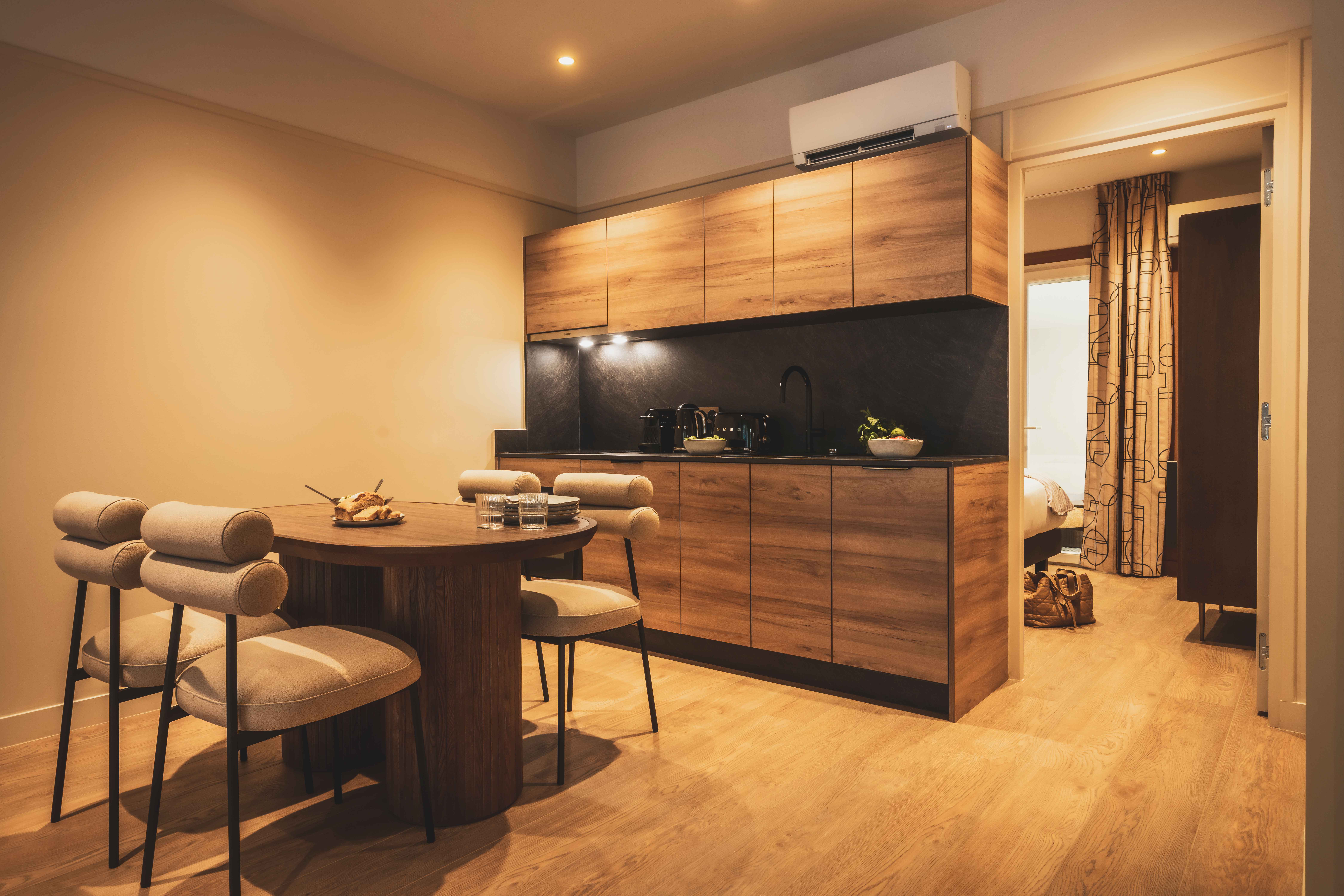 image Warm, fully equipped kitchenette with modern wood finishes — perfect for preparing meals in the comfort of your apartment.
