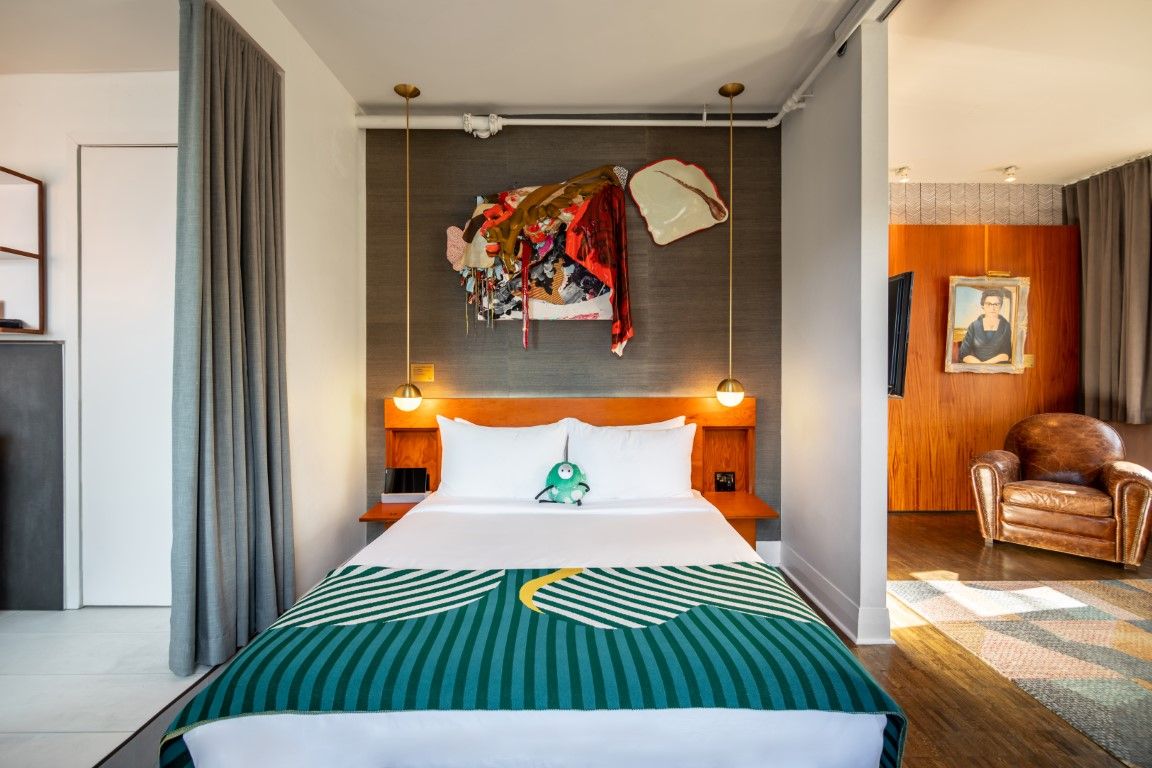 image The Classic Queen room exudes coziness with its soft linens and playful art, complemented by the warmth of exposed brick and boutique lighting.