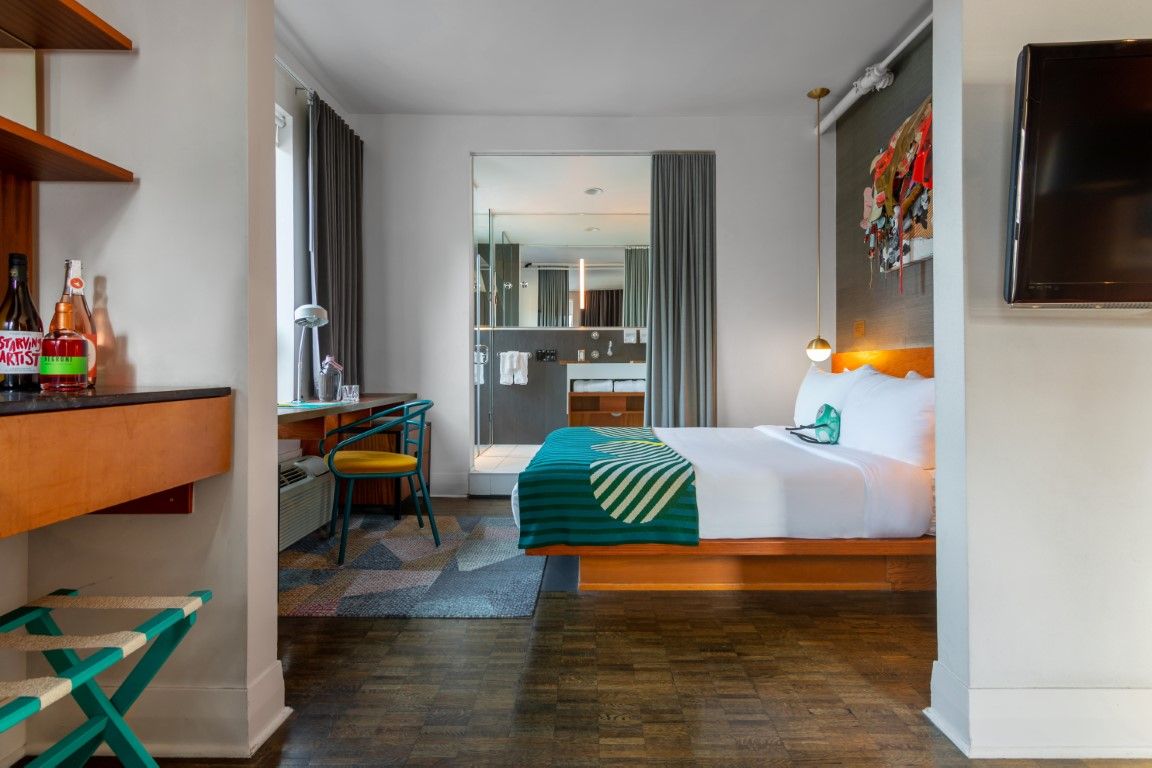 image Featuring a stylish glass-paneled shower and inviting workspace, the room balances modern comfort with artistic flair and vibrant decor.