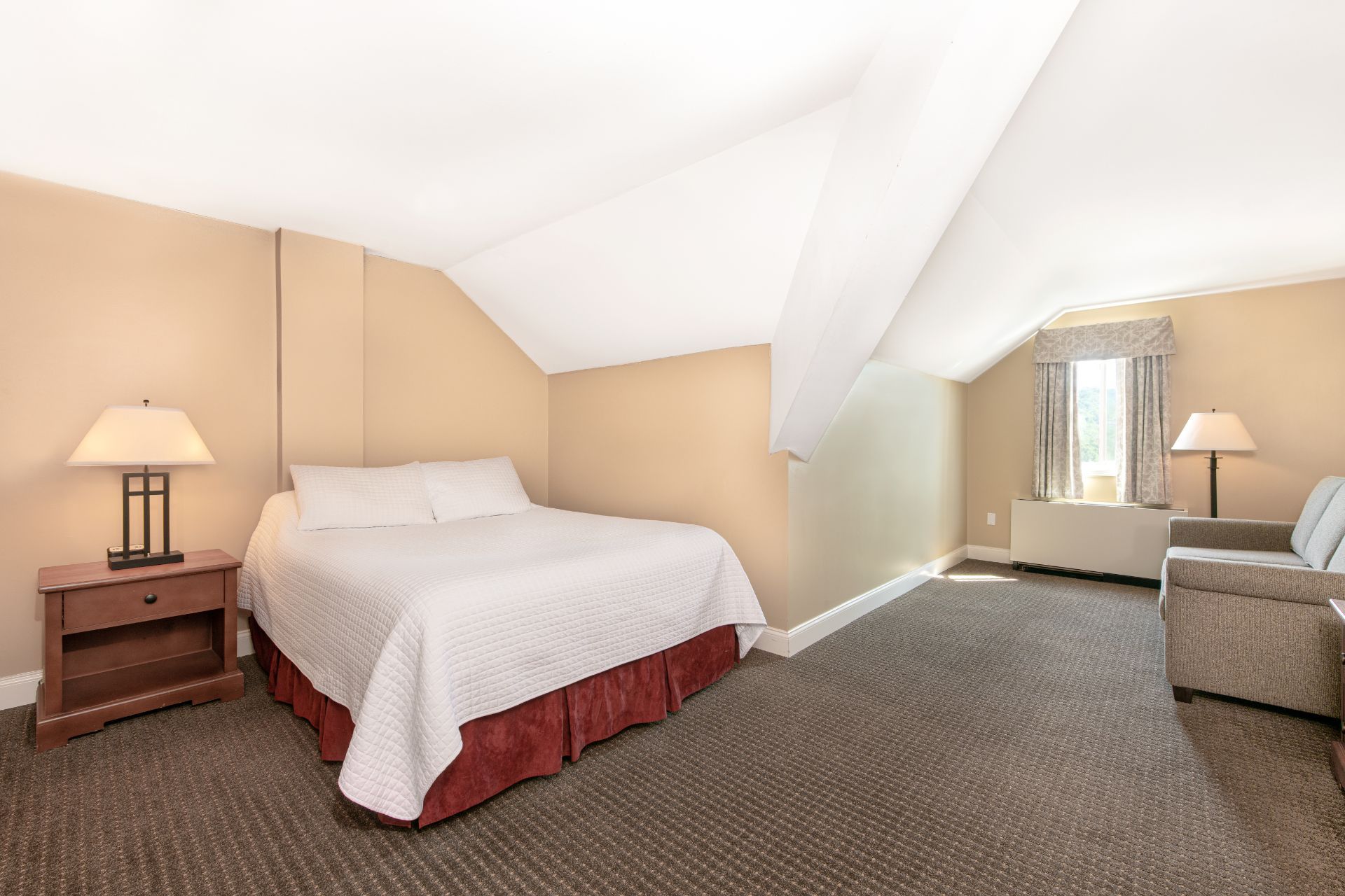 image Spacious loft-style bedroom with vaulted ceilings, cozy furnishings, and natural light for a tranquil, inviting atmosphere.