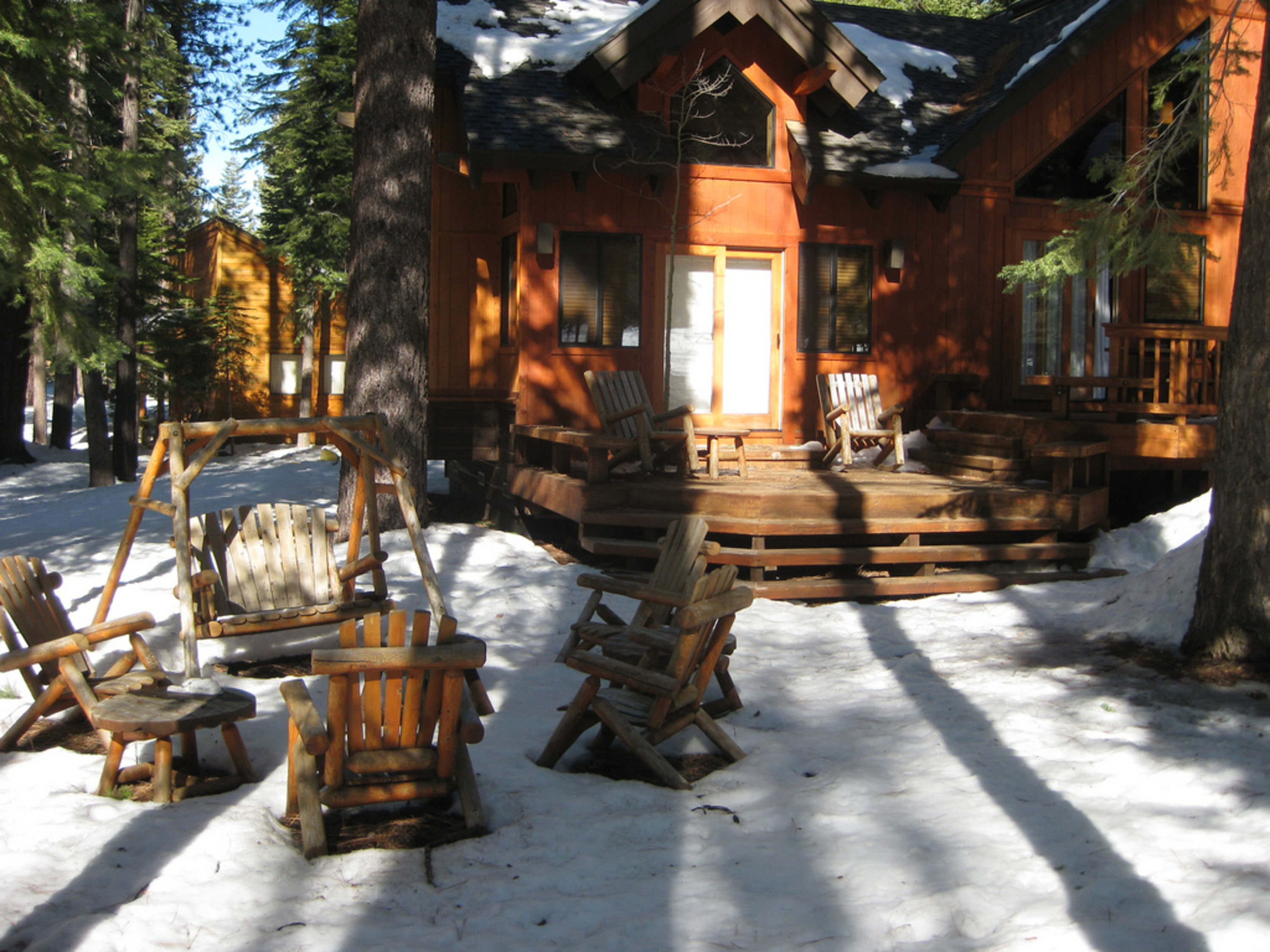 image The charming exterior of the Northstar home is surrounded by snow-covered grounds, featuring inviting wooden seating areas perfect for enjoying the serene forest backdrop.