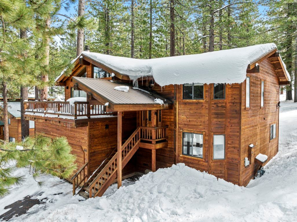 image This charming Northstar home is surrounded by snow-laden pines, showcasing its inviting wooden exterior and spacious entryway.