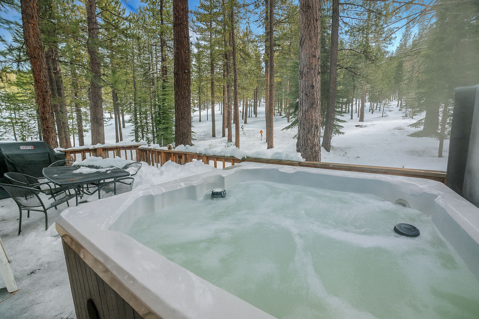 image Relax in the private hot tub surrounded by towering pines and winter scenery, offering a serene escape.