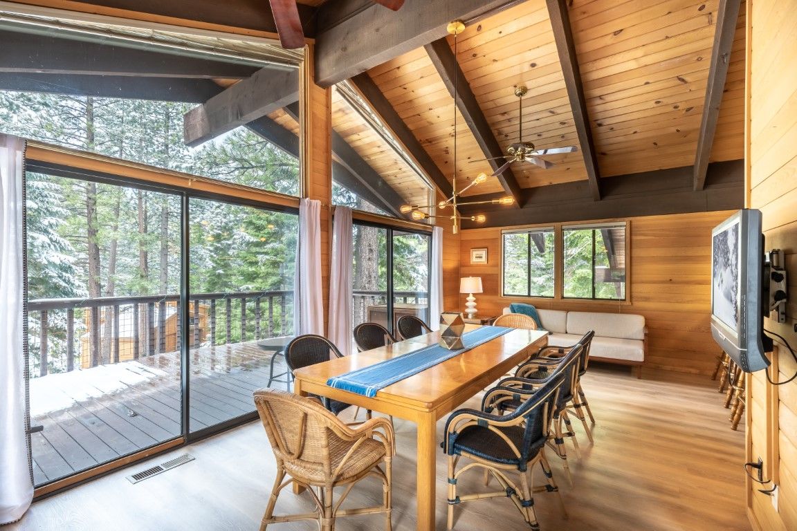 image Inviting dining area with a large table and panoramic windows that provide a beautiful view of the forest.