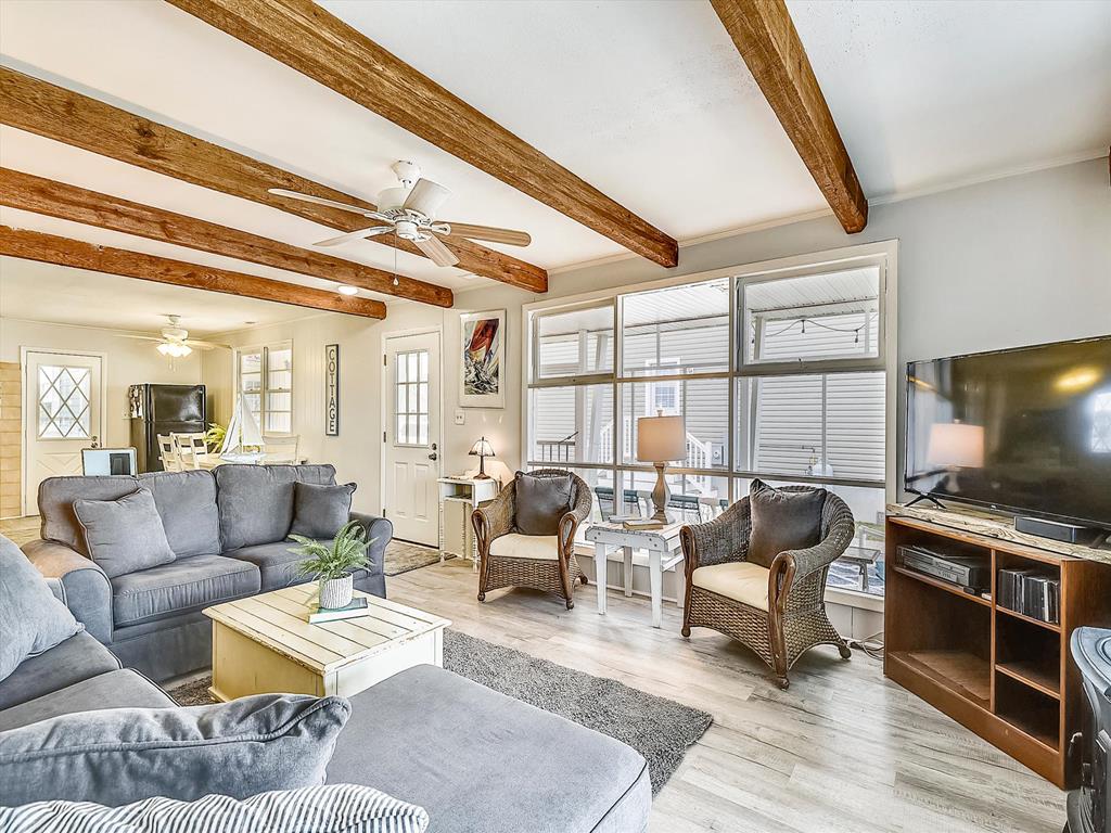 image Experience the charm of this inviting living area with exposed wooden beams, comfortable seating, and abundant natural light, ideal for gathering with family and friends.