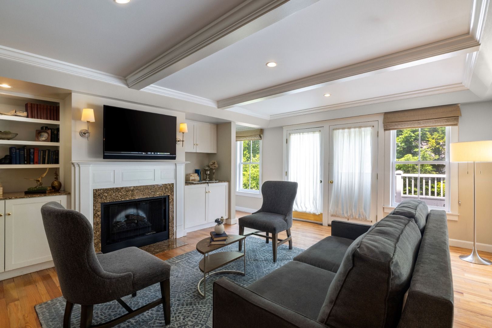image The living area boasts a comfortable seating arrangement around a decorative coffee table, featuring a fireplace and large windows that flood the space with natural light.