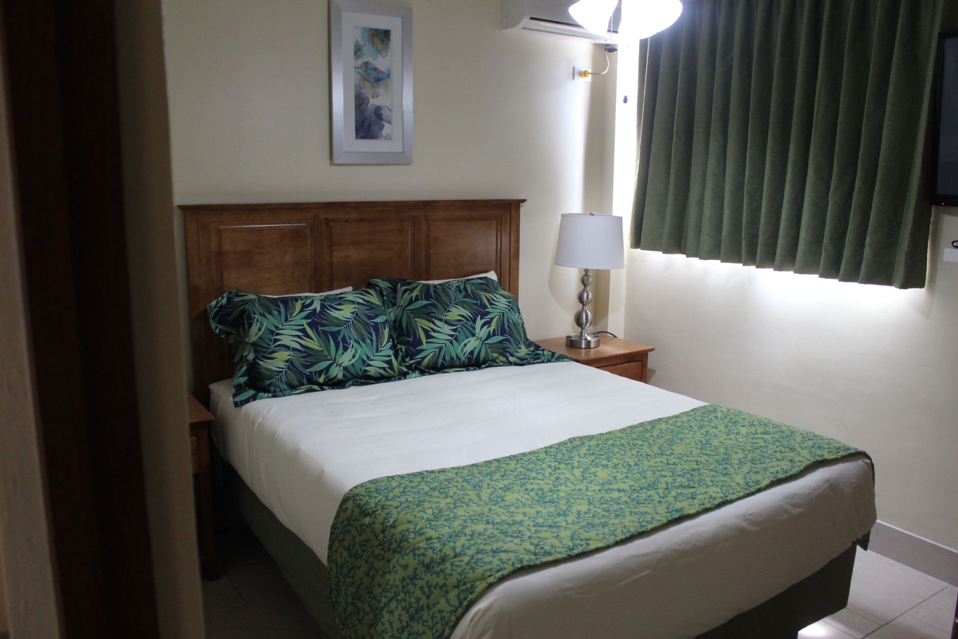 image Inviting second bedroom with comfortable furnishings, adorned with tropical-themed pillows and ample natural light.