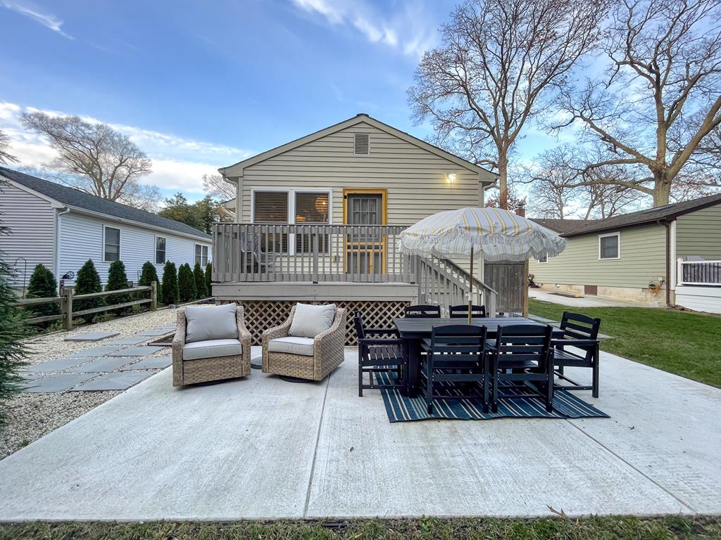 image Relax on the spacious patio, perfect for summer BBQs with family and friends, complete with comfortable seating and a charming umbrella for shade.