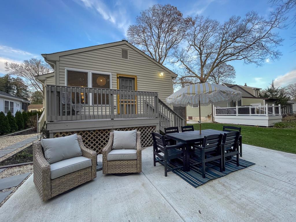image Enjoy al fresco dining on the spacious deck, where contemporary outdoor seating and a colorful umbrella create the ideal spot for sunset gatherings.