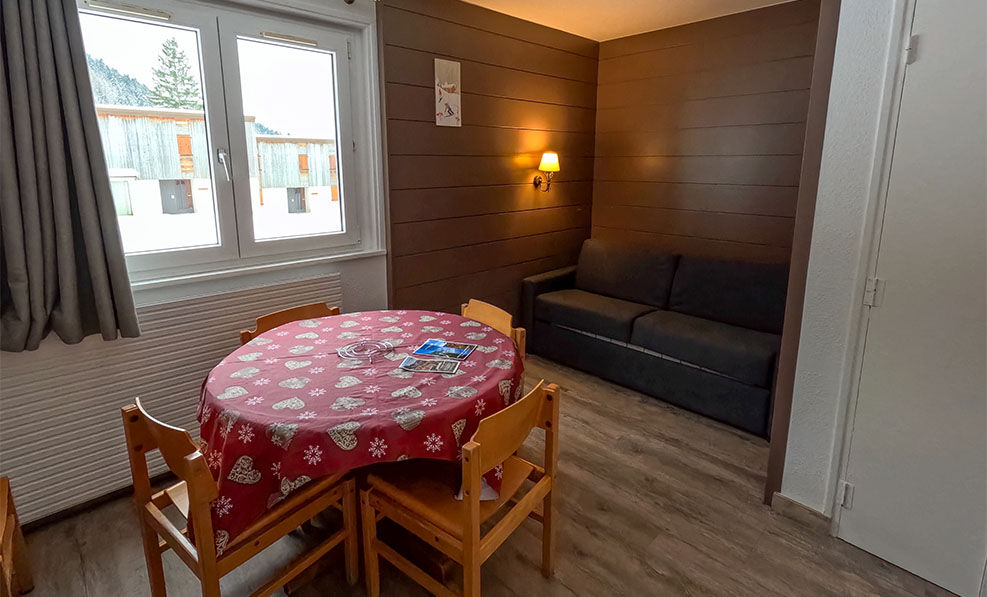 image The inviting living space showcases a comfortable sofa and large windows that frame stunning views of the snowy Jura mountains.