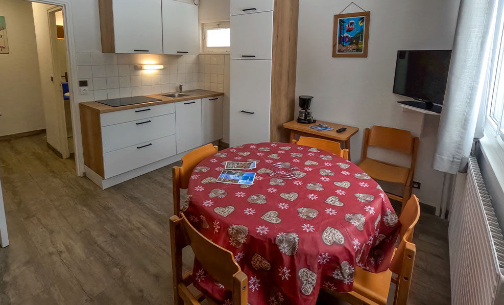 image A bright and modern kitchen setup invites you to prepare meals, with a welcoming dining table at the center, fostering togetherness in a warm, mountain-inspired ambiance.