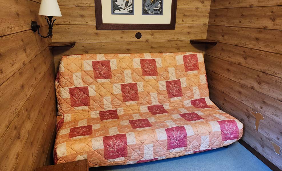 image The traditional fold-out sofa bed adds a touch of comfort and nostalgia, inviting guests to relax in this alpine-inspired nook.