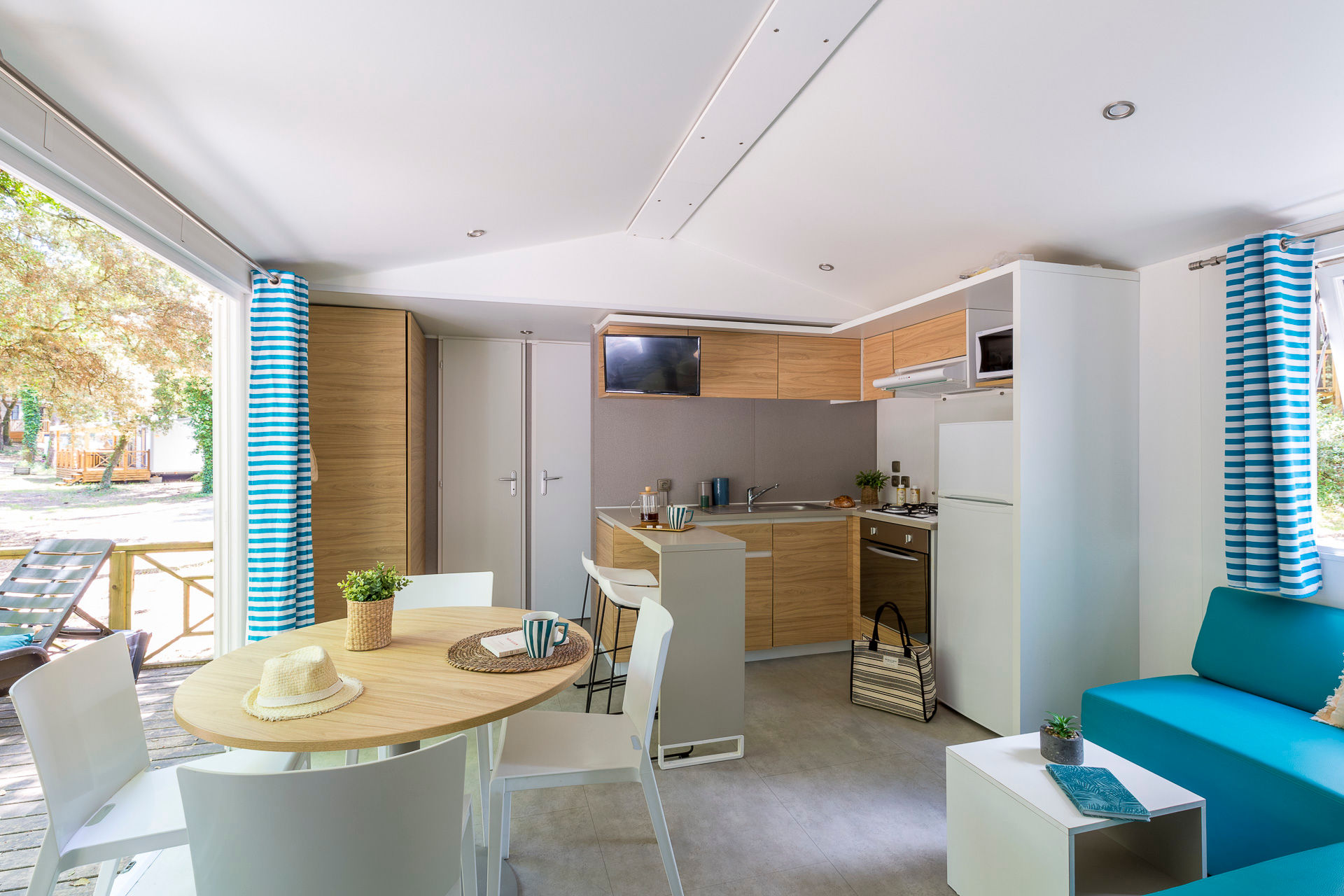 image The airy living area features a cozy couch and dining space, complemented by large windows that provide natural light and views of the lush landscape.