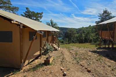 Nestled in the serene landscapes of Provence, the Tente Lodge Woody Plancha offers a perfect family retreat with spacious accommodations set against a backdrop of lush greenery and a tranquil water reservoir.