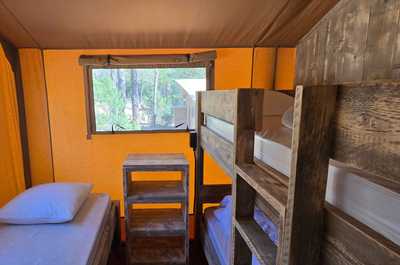 The children's area features cozy bunk beds, perfect for family adventures, complemented by vibrant orange walls and scenic views.