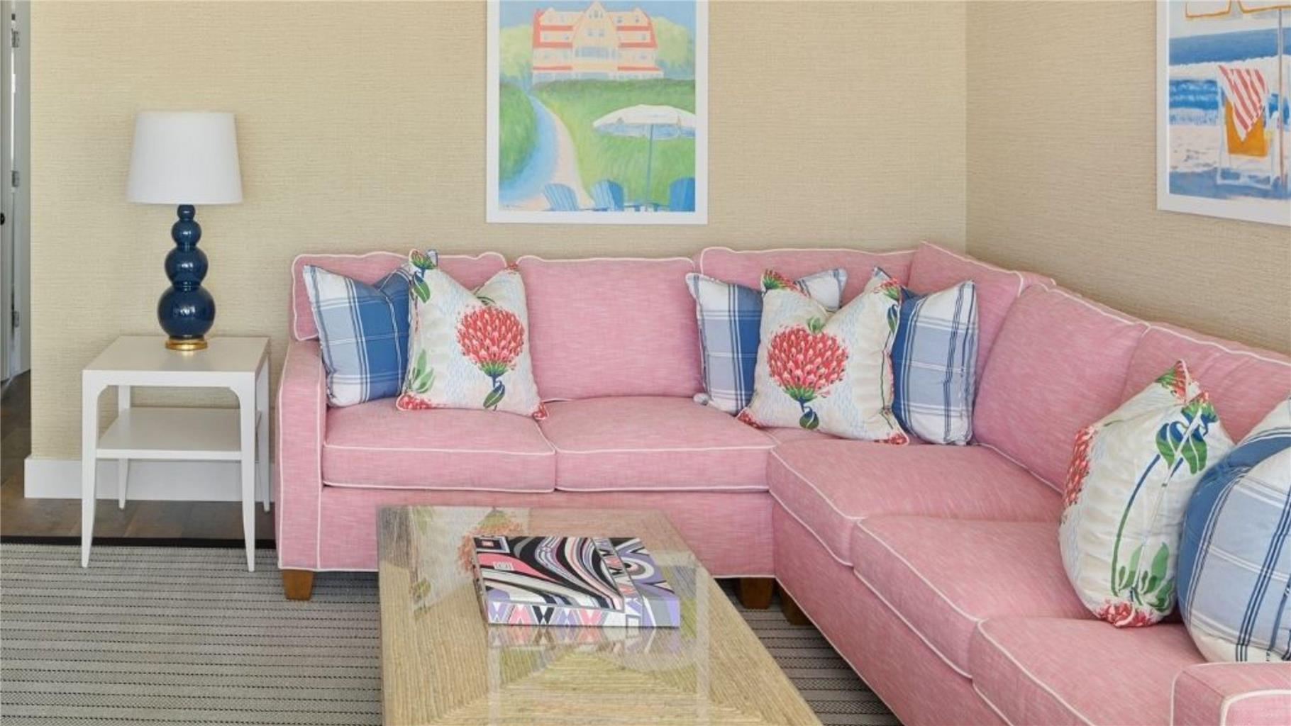 image The inviting living room features a spacious pink sectional, bright decorative pillows, and a contemporary coffee table, creating a vibrant and cozy atmosphere.
