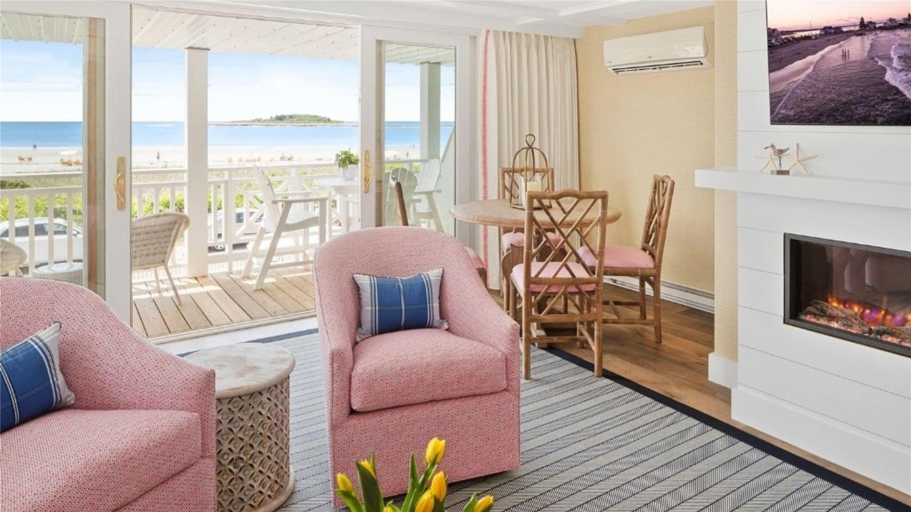 image Enjoy stunning ocean views from the cozy living space, featuring pink chairs and a stylish fireplace, perfect for relaxation.