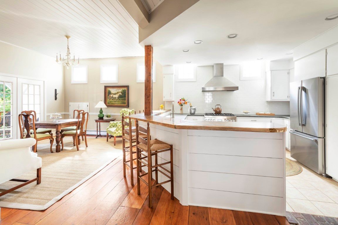 image An open-concept kitchen and dining area combines functionality and style, featuring a central island and warm natural light from large windows.