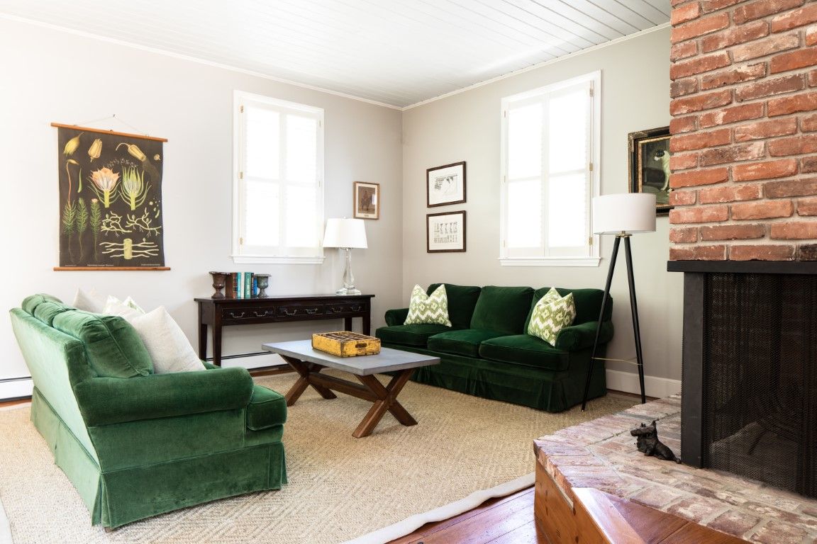 image The cozy living room is adorned with plush green sofas, offering a perfect spot for relaxation next to the charming brick fireplace.
