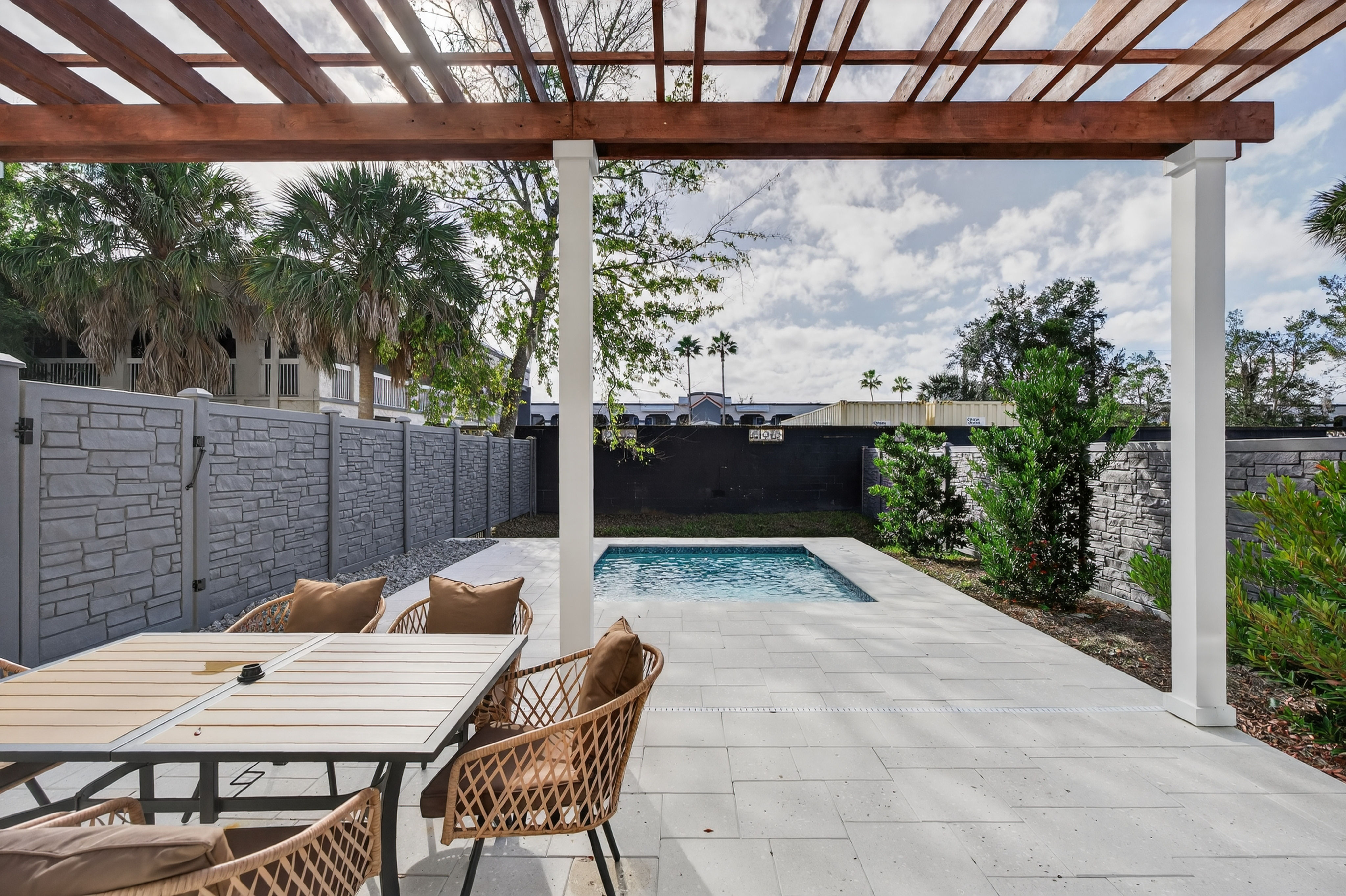 image Relax in this lovely outdoor space featuring a private pool and pergola-shaded seating, surrounded by lush greenery.