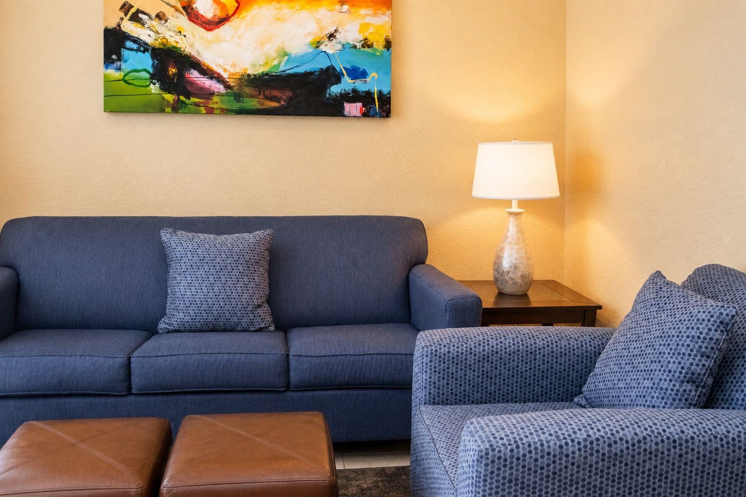 image The vibrant artwork above the blue sofa and a softly glowing lamp create a lively focal point, enhancing the charm of this comfortable living space.