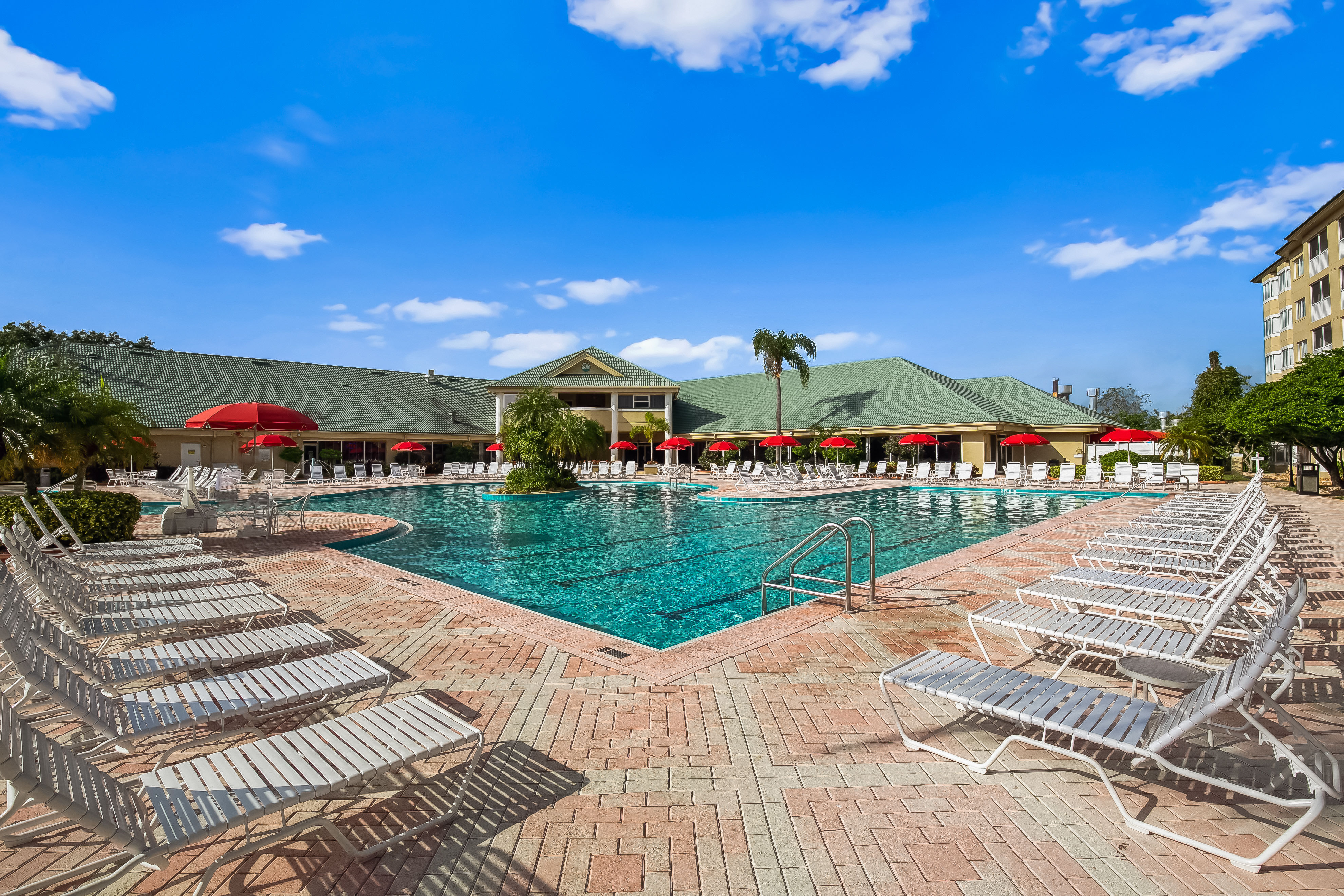 image Relax in style at the inviting pool surrounded by lounge chairs and vibrant umbrellas.