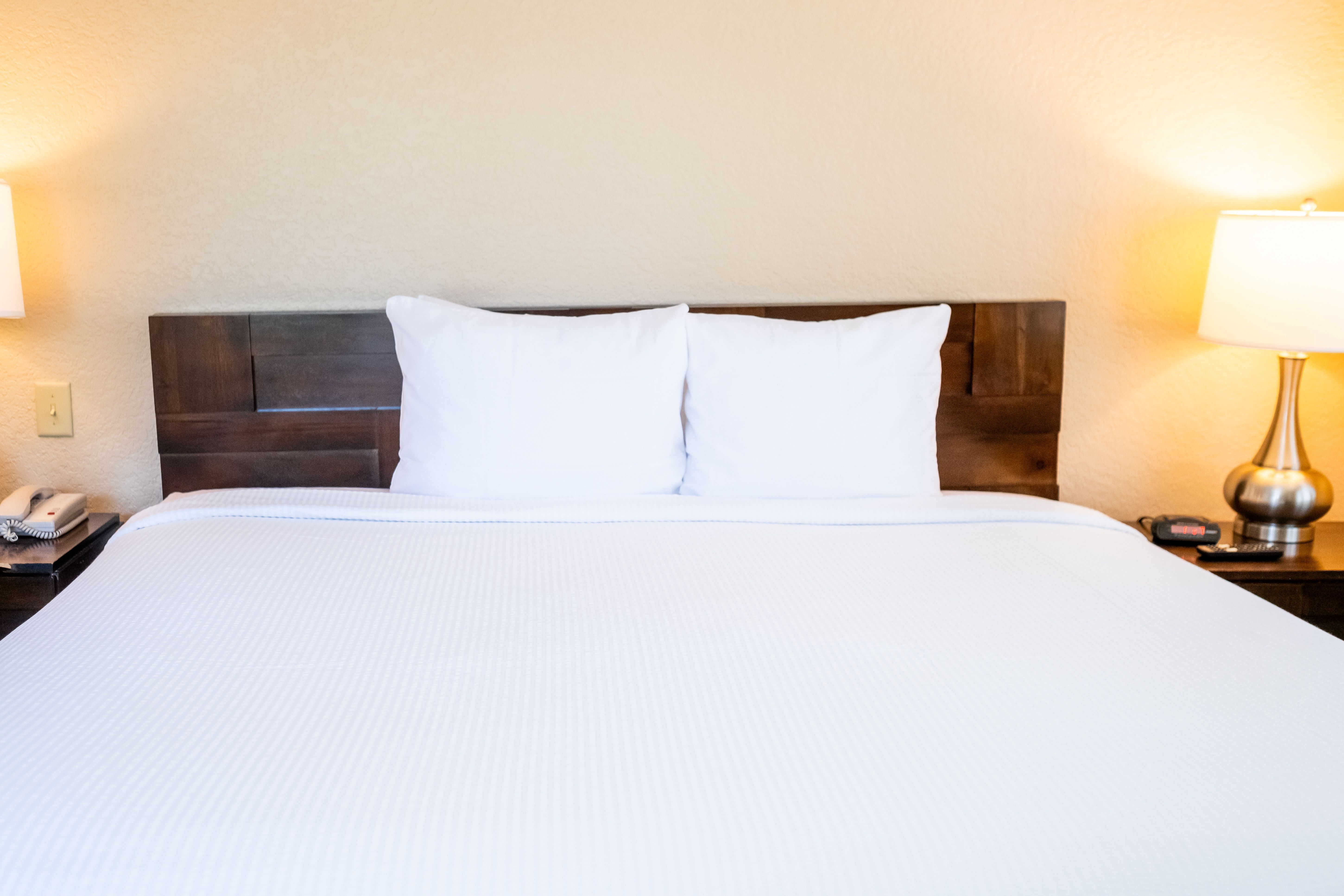 image Comfortable bed with crisp linens and bedside lamps creating a relaxing atmosphere.