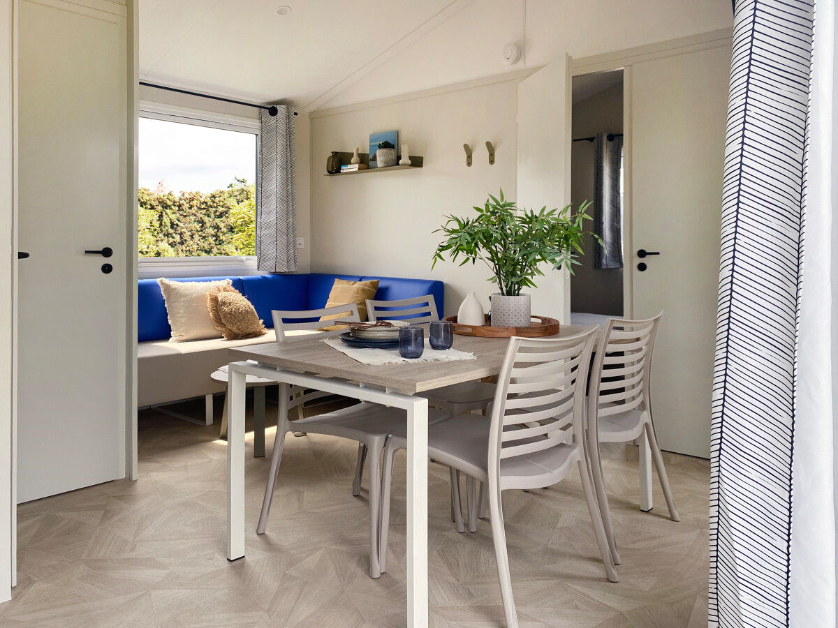 image The cozy dining area showcases a sleek table surrounded by comfortable seating, accented by cheerful decor and a vibrant blue bench.