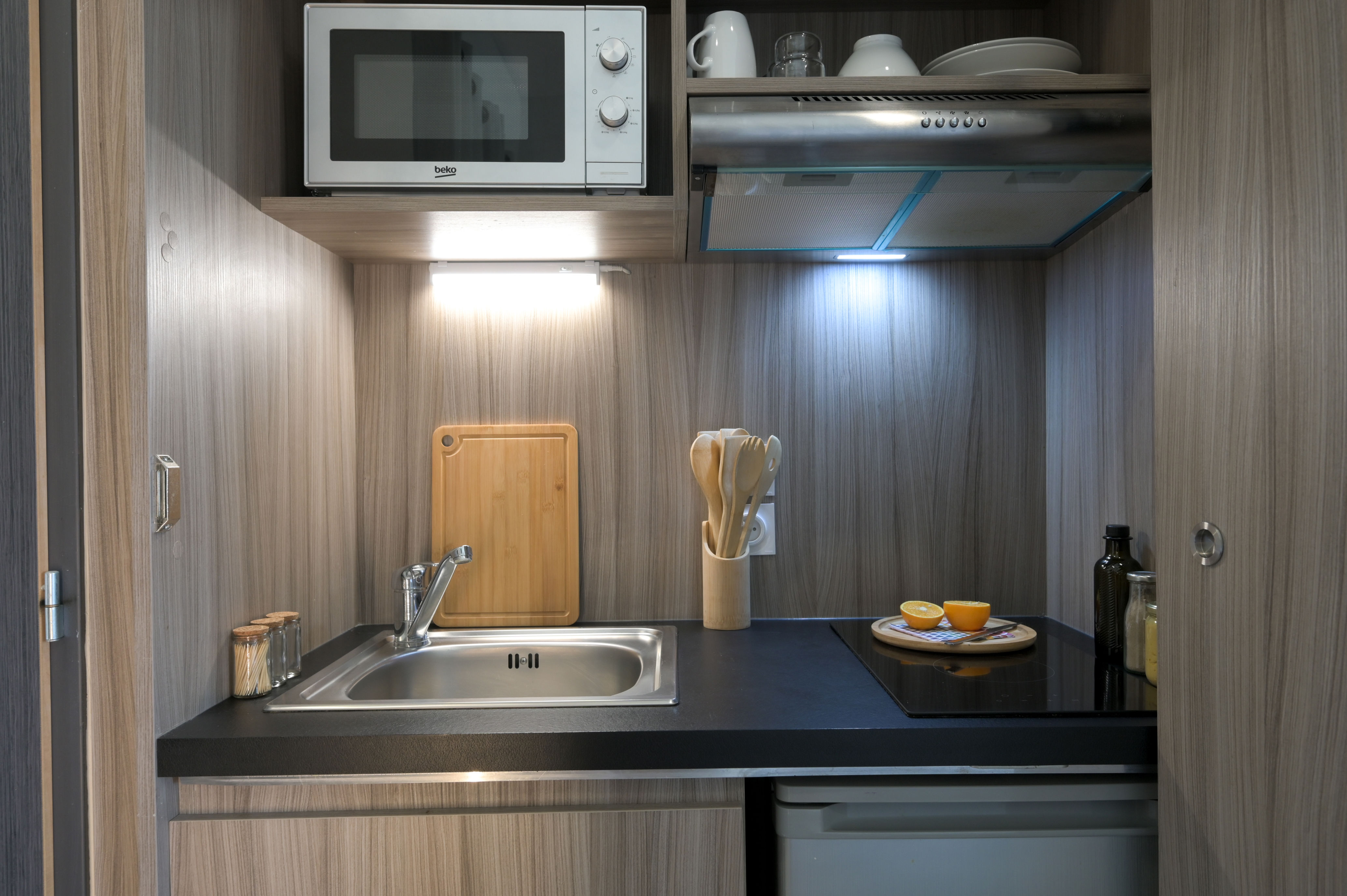 image Modern kitchenette with wood finishes and integrated appliances for independent stays.