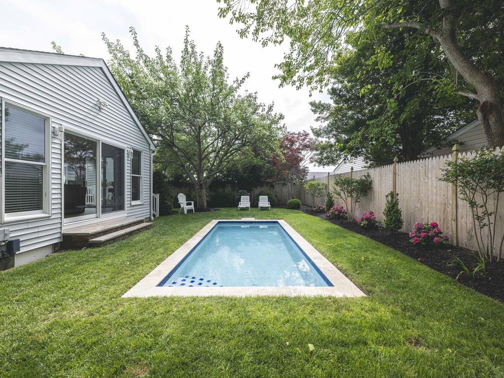 image Sunlit backyard pool area framed by vibrant landscaping and comfortable seating.