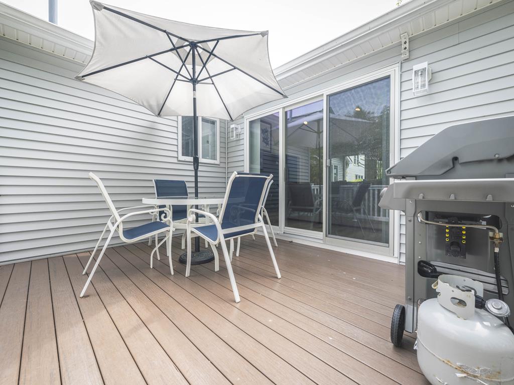 image Cozy deck dining area with a gas grill and patio umbrella for shaded outdoor barbecues.