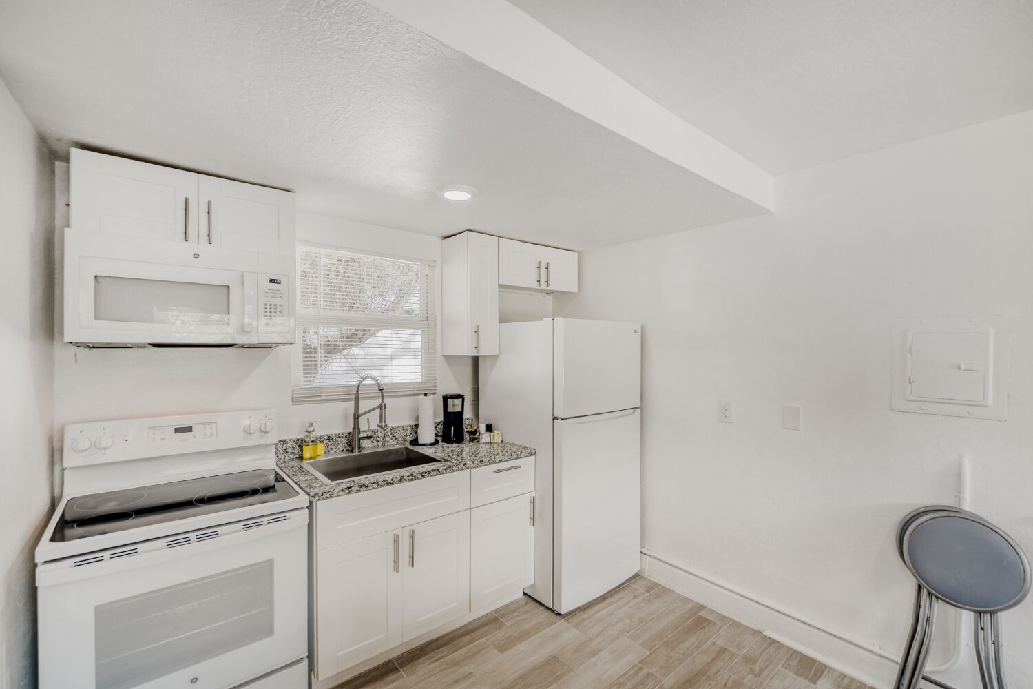 image Modern kitchenette features a stovetop, full-size fridge, microwave, coffee maker, and ample cabinetry for all your culinary needs.