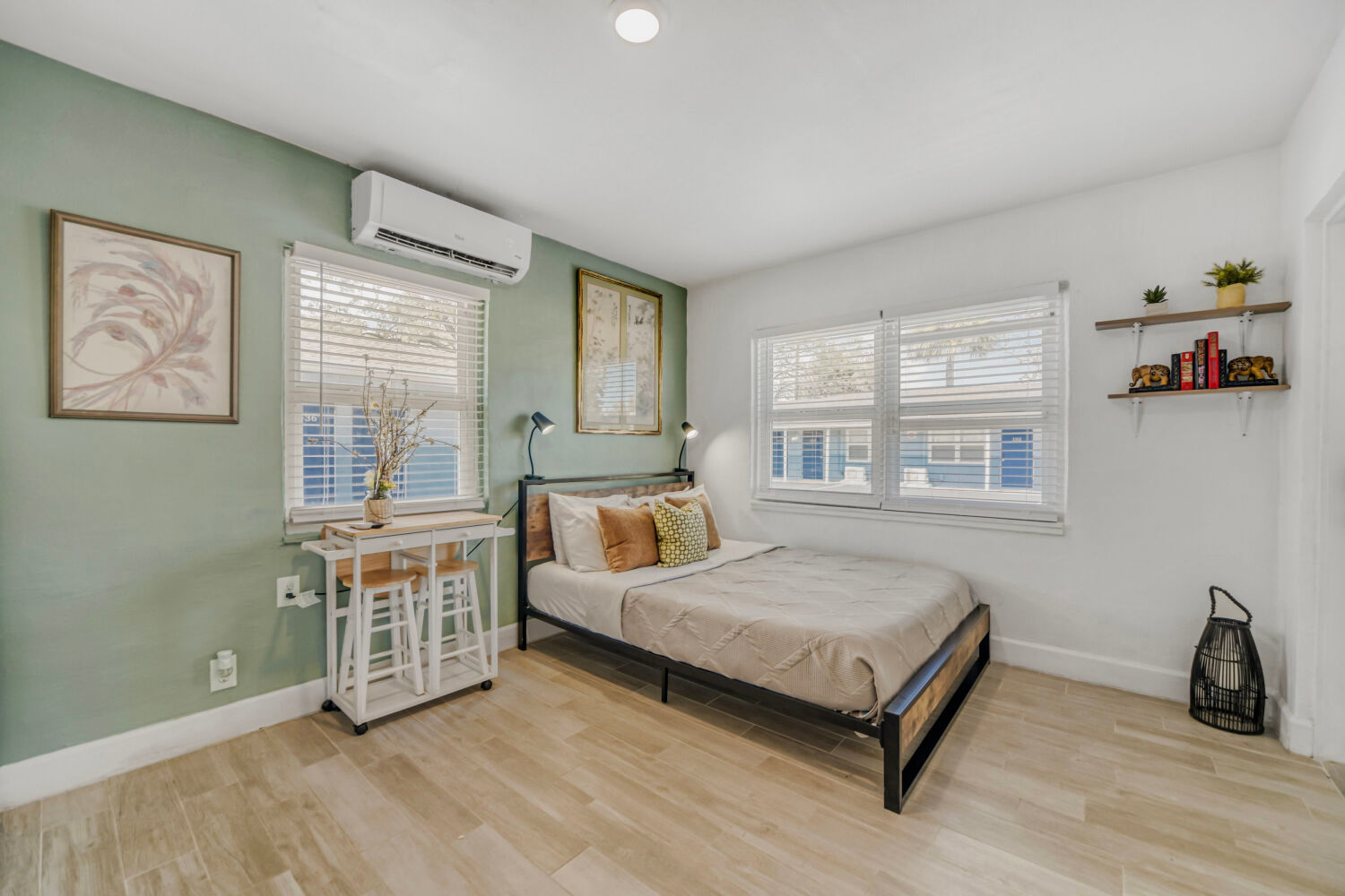 image Bright studio with a queen bed, wall-mounted TV, and simple furnishings in a compact layout.