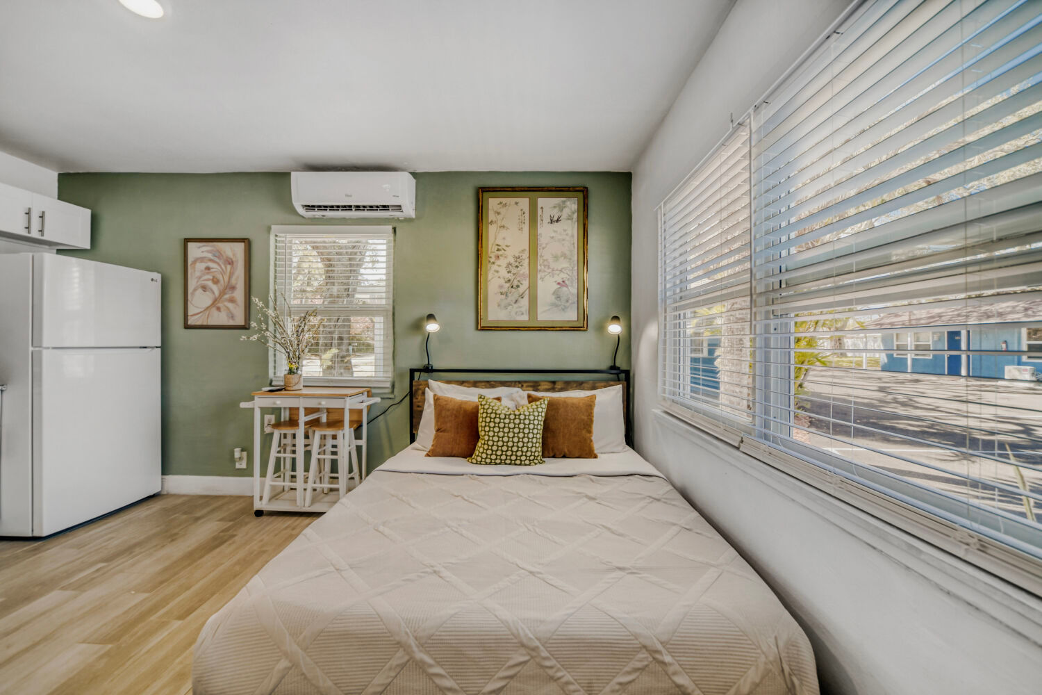 image Sleeping area with a queen bed and nearby workspace in a compact studio setting.