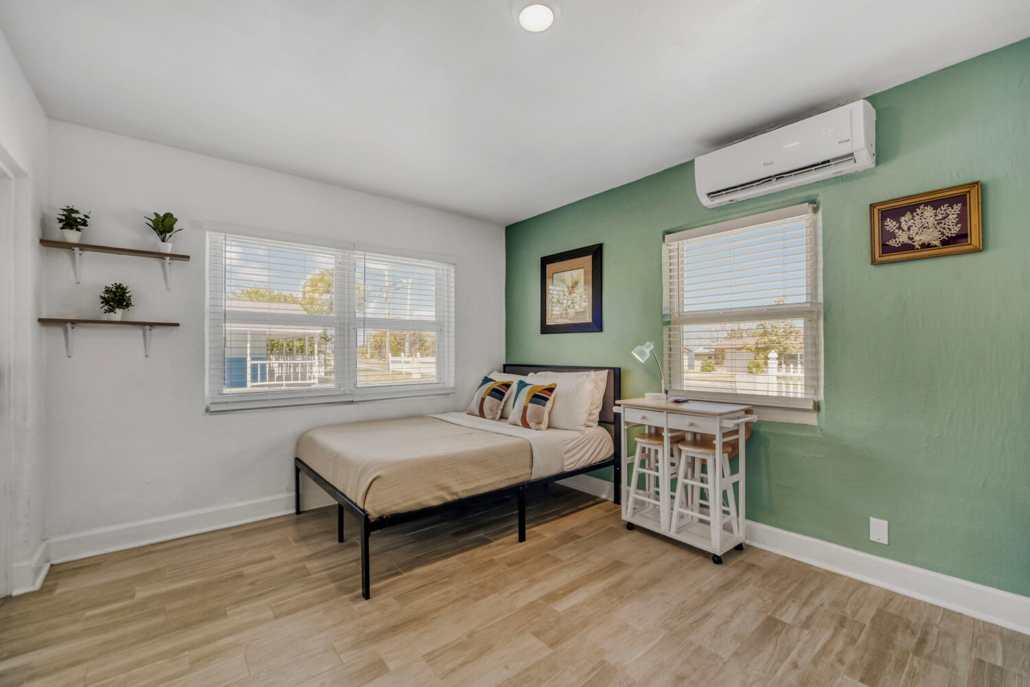 image Compact studio with a full bed, wall-mounted TV, and natural light from nearby windows.