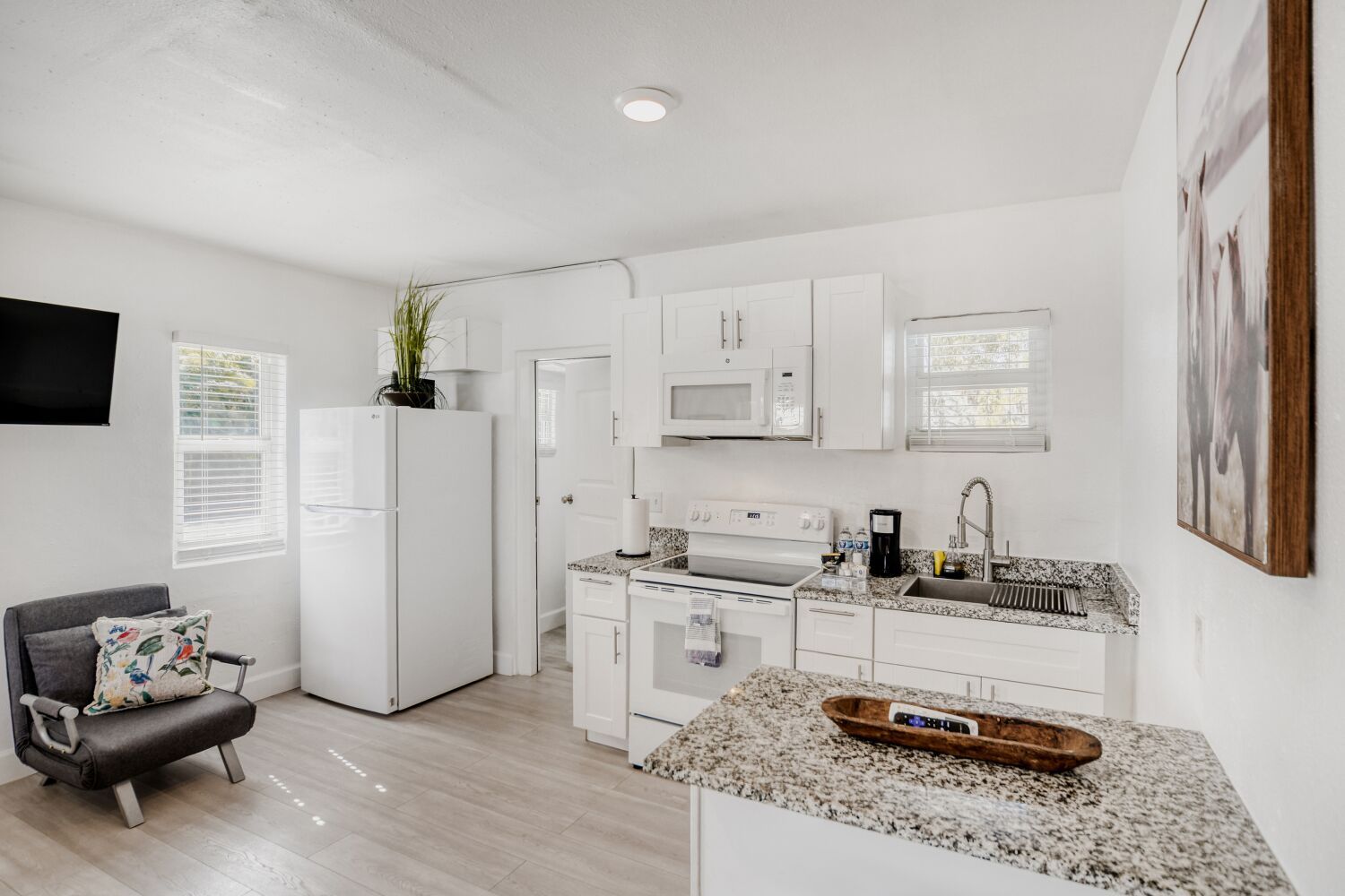 image Airy living space includes a plush armchair, breakfast bar, and flat-screen TV, creating an inviting setting to unwind or entertain.