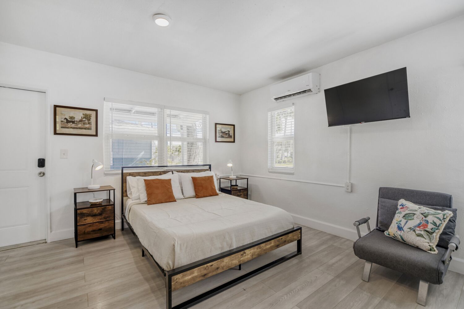 image Chic studio sleeping space showcases a cozy bed with crisp linens, wall-mounted TV, AC, and modern furnishings for a relaxing escape.